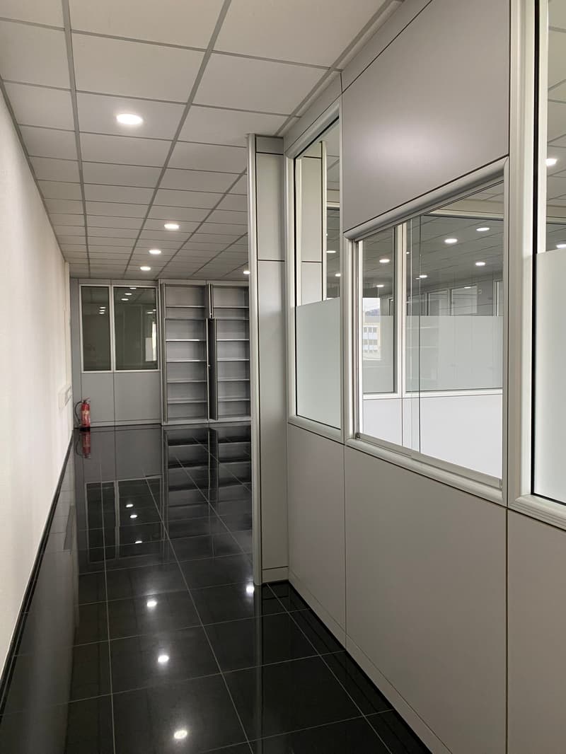 Empty hallway with modern white walls, ceiling, tiled floor, and large windows