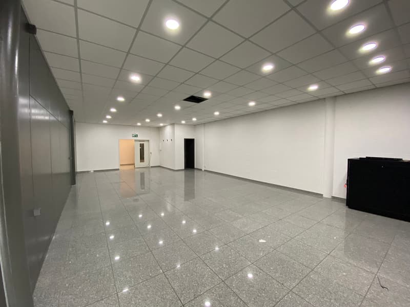 Empty room with white walls, gray tiled floor, and ceiling lights