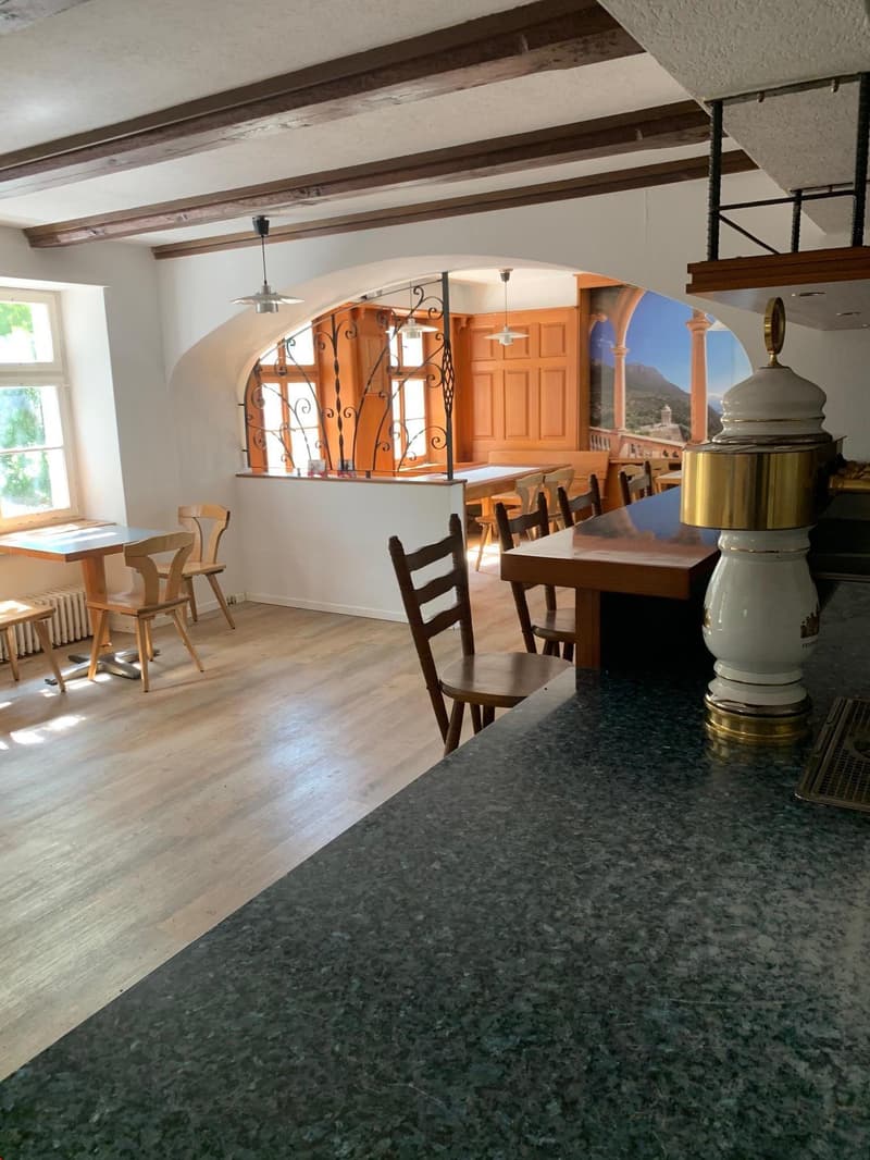 Rustic dining room with wooden beams, arched doorway, wooden tables and chairs, and a fireplace