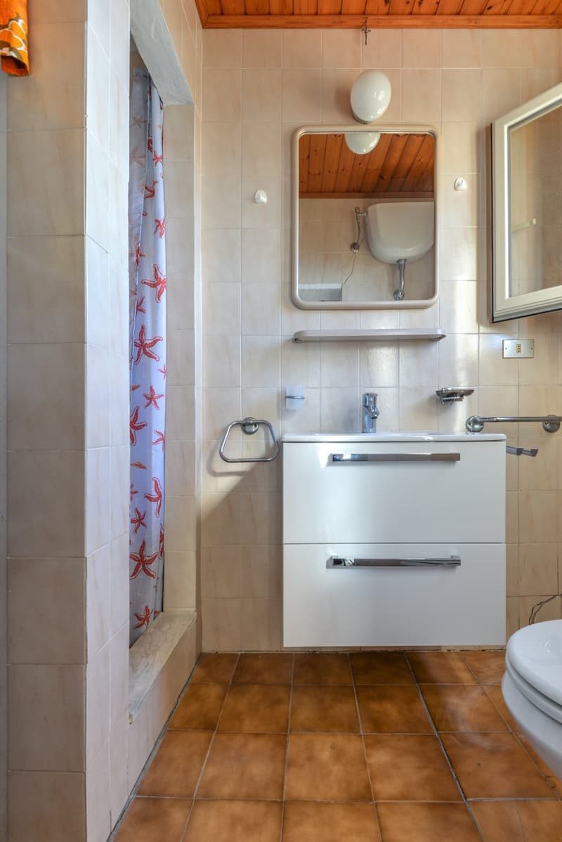 Bathroom with tile flooring, white vanity with drawers, mirror, and shower curtain with starfish pattern