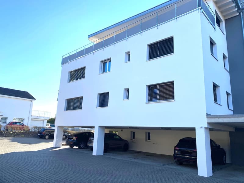 3 story building, white exterior, multiple windows, covered parking area, two levels of parking