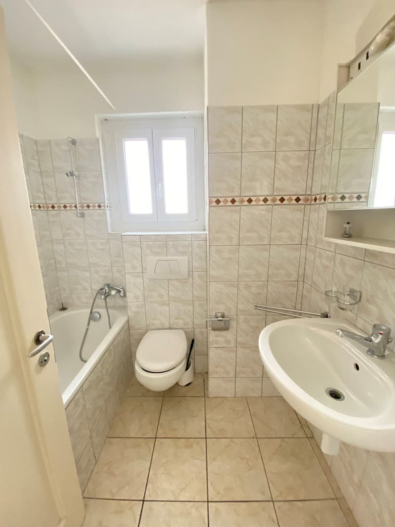 Bathtub, toilet, sink, shower, tile flooring, white walls, white fixtures