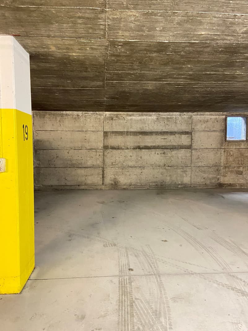 underground room, concrete walls, numbered yellow post, small window, tire marks