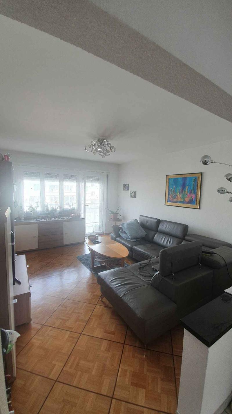living room, black leather sofa, wooden table, wooden flooring, balcony, picture frames, window with curtains