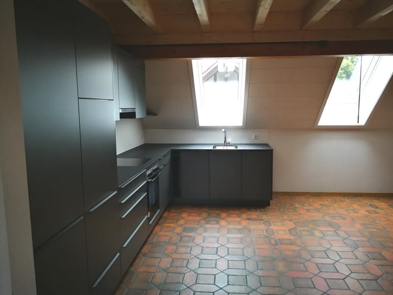 Modern kitchen with black cabinets, hexagonal tiled floor, and a sink with a faucet.