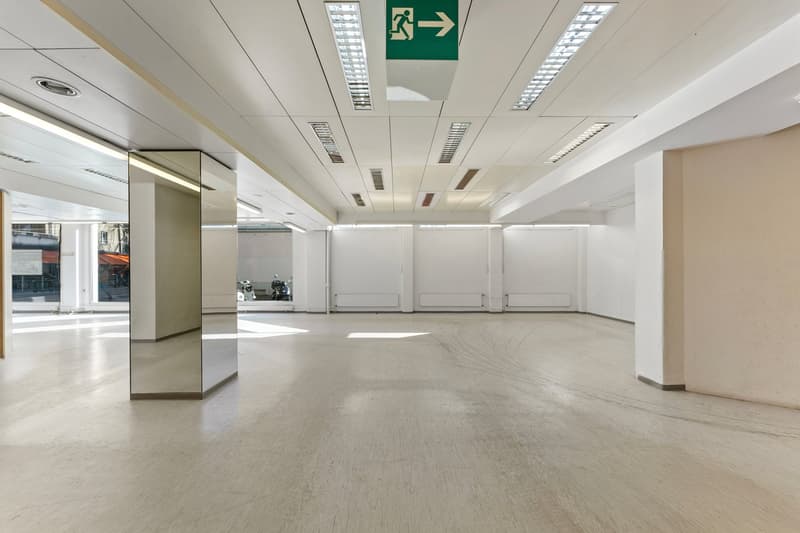 Empty room, white walls, white ceiling, white floor, large mirror, emergency exit sign