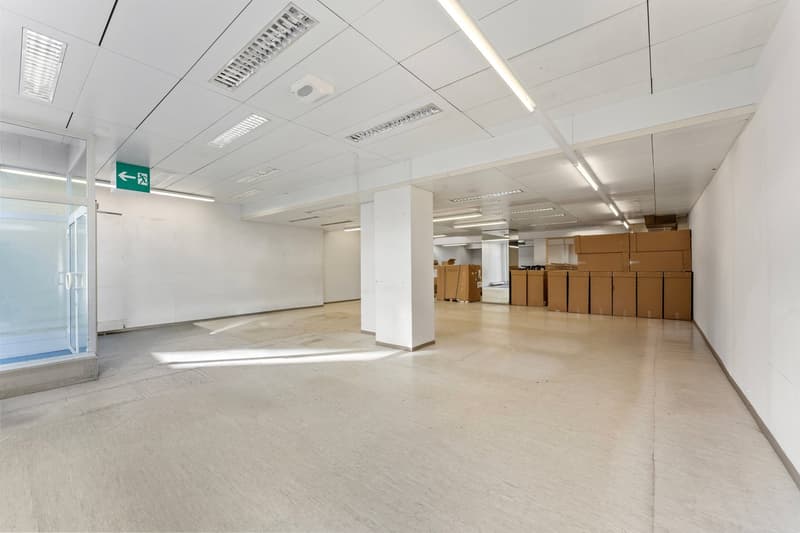 Empty room, white walls, white ceiling, white floor, glass door, exit sign, stacks of boxes