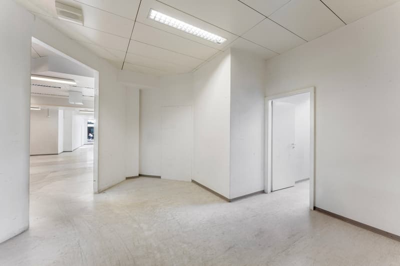 Empty room with white walls, ceiling, and floor. Two doors on the right side.