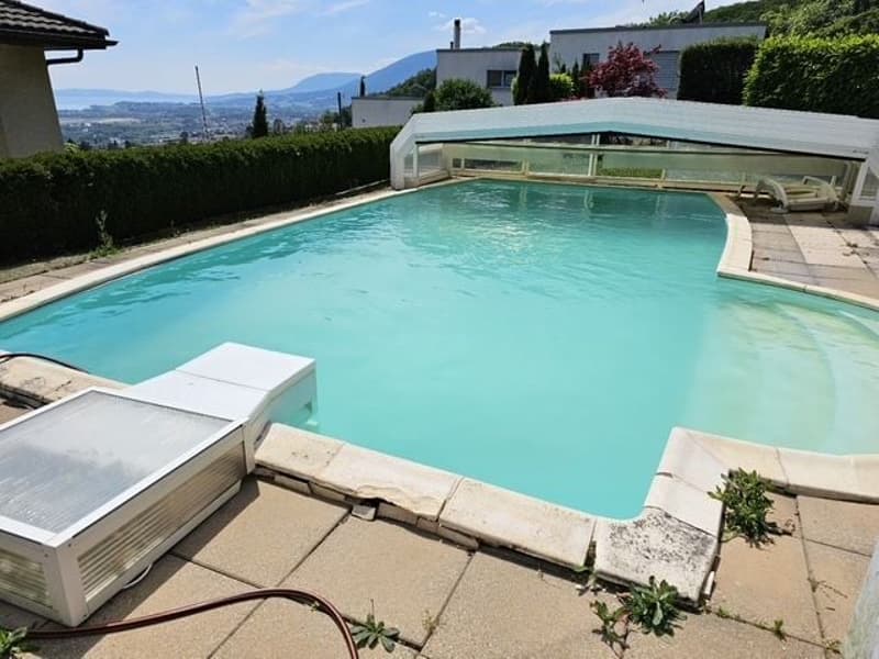 large rectangular swimming pool, glass canopy, sunbathing chairs, surrounding tiled area, distant view of mountains