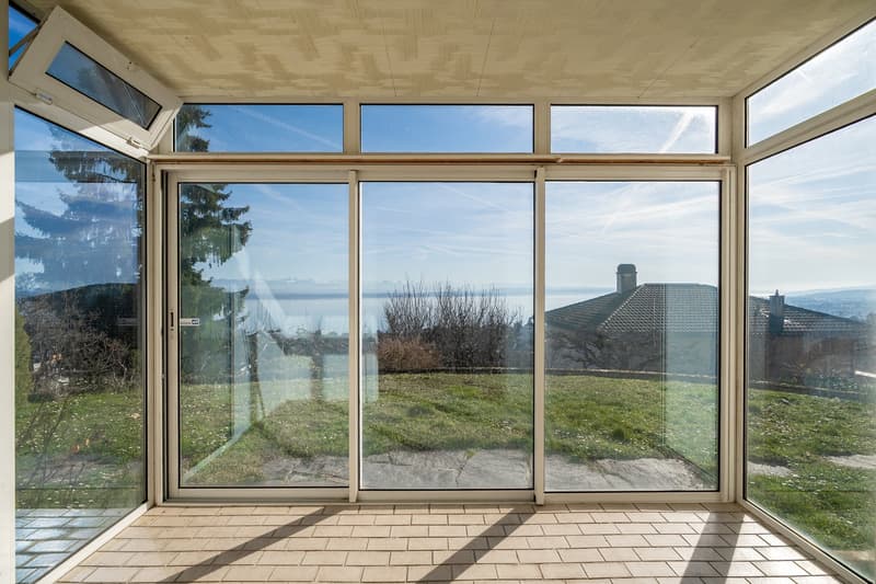 Sliding glass doors, large windows, brick flooring, open to grass field, view of lake