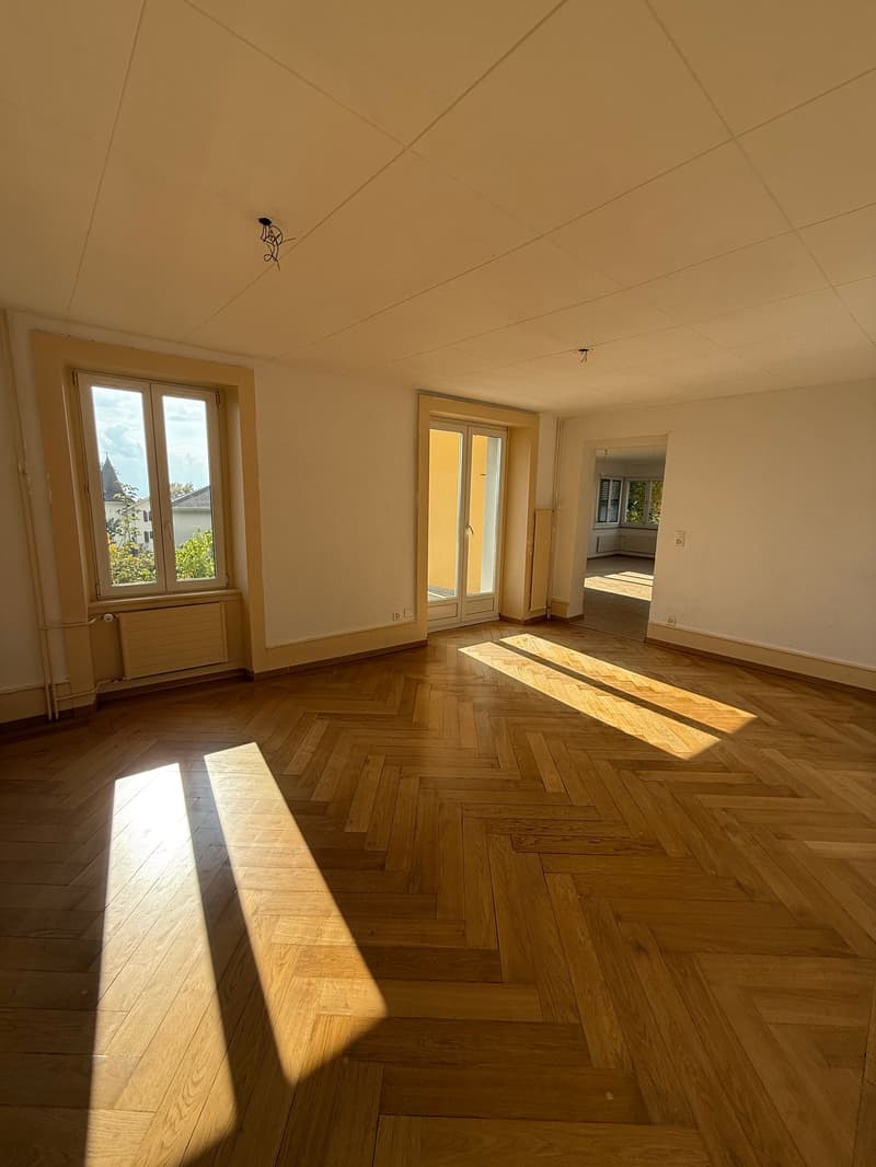 empty room with parquet flooring, two windows, double sliding doors, ceiling mounted light fixture, heating radiator
