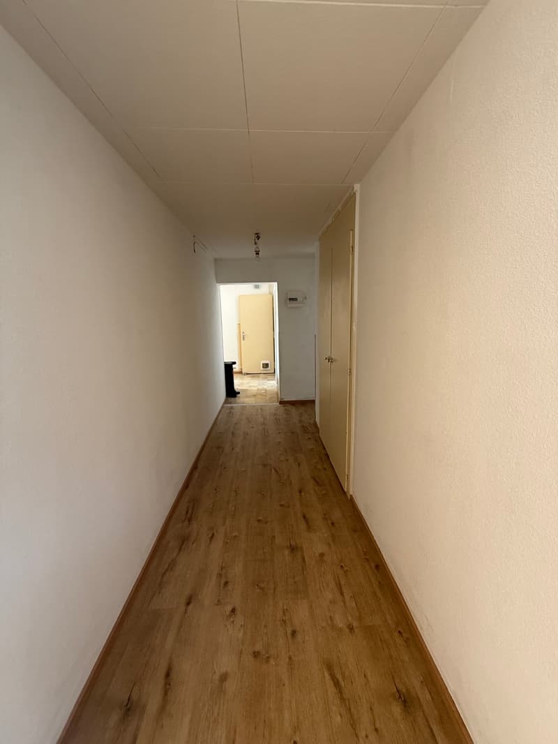 wooden floor, white walls, doors on both sides