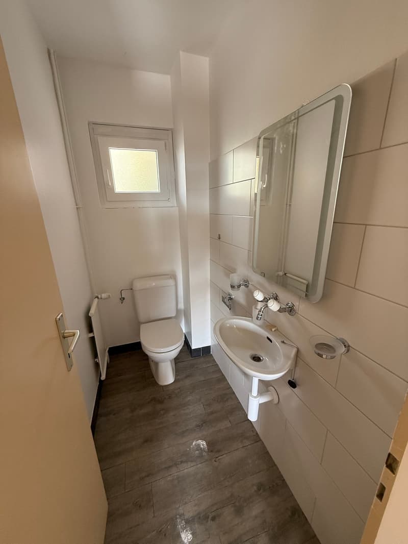 Small bathroom with toilet, sink, mirror, radiator
