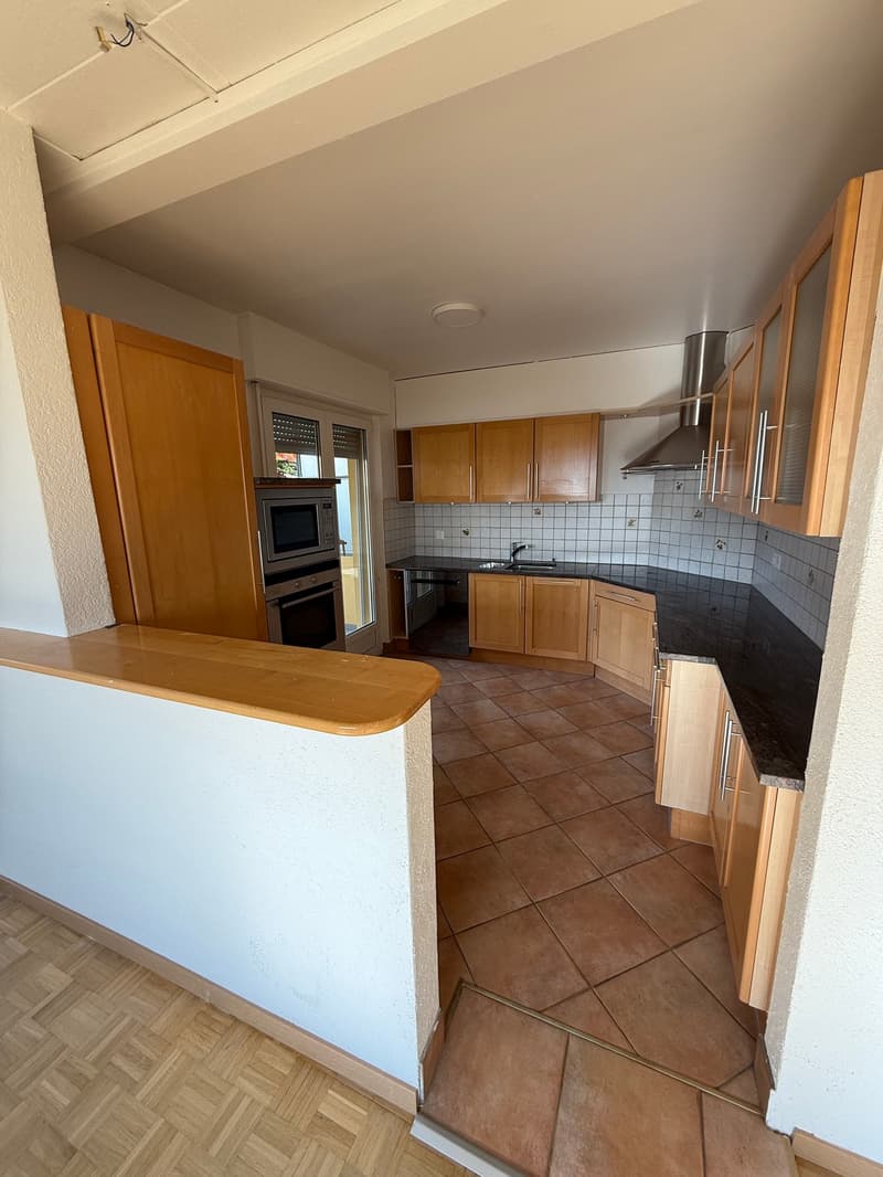 modern kitchen with wooden cabinets, granite countertops, black tiles on floor, electric oven, microwave, stainless steel hood, and a sink