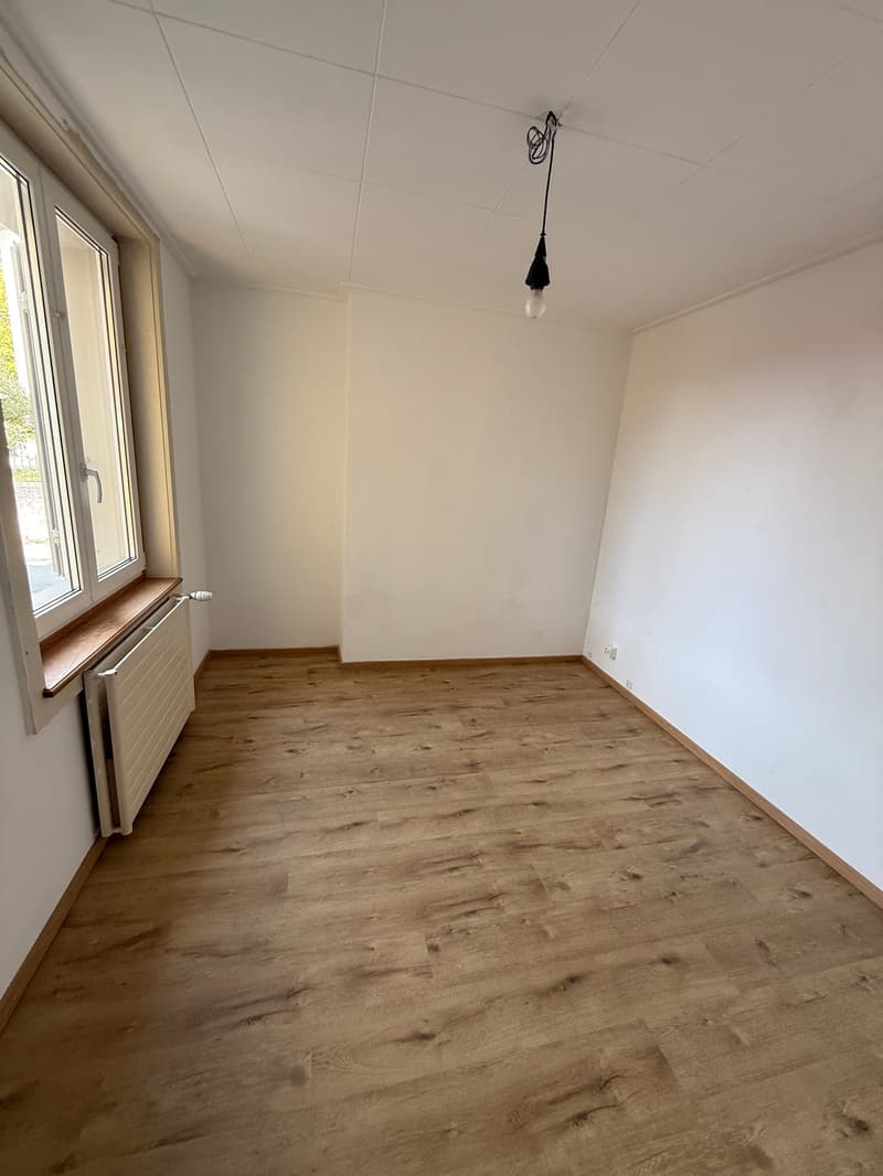 empty room with white walls, wooden floor, radiator, window