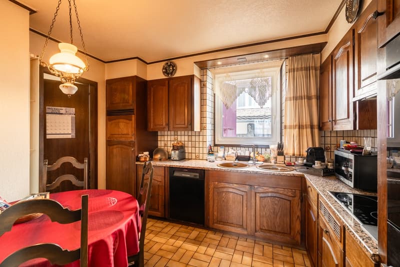 wood cabinets, tiled floor, granite countertops, dishwasher, double sink, wooden chairs, red table
