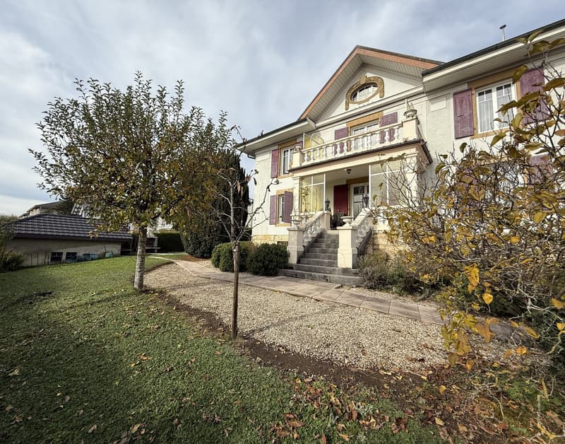 large 3 story house, white walls, brown roof, balcony, staircase, small yard