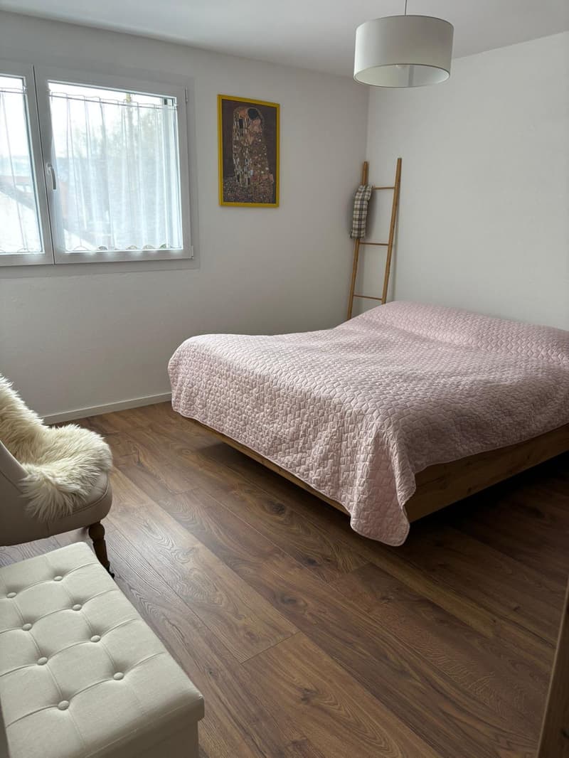 bedroom with wooden floor, bed, chair, wooden ladder, picture frame, window with curtains