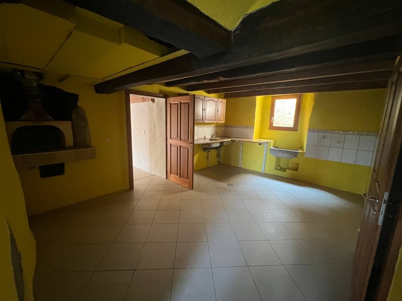 Spacious kitchen with wooden cabinets, tiled floor, and a window. There is a washing machine visible in the room.