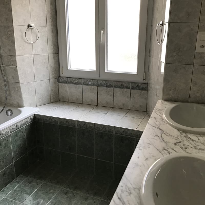 Bathroom with bathtub, two sinks, window, tiled walls and floor