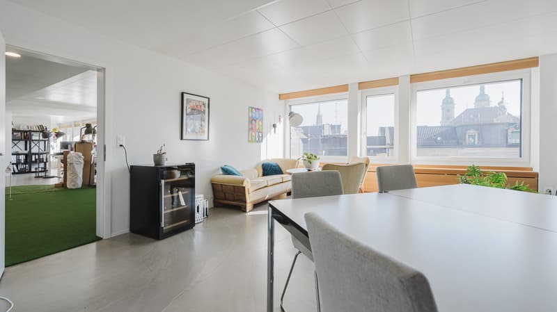 Open living space with couch, table, chairs, bookshelves, and picture frames.