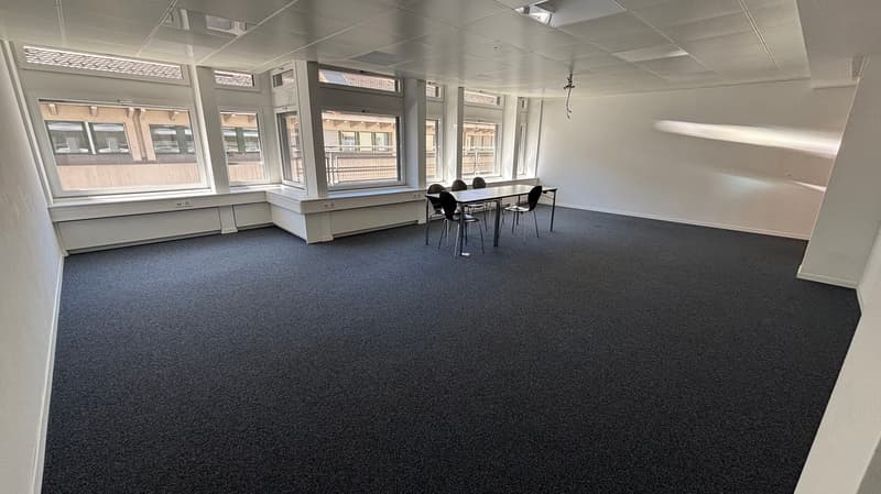 empty room, carpeted floor, large windows, table and chairs