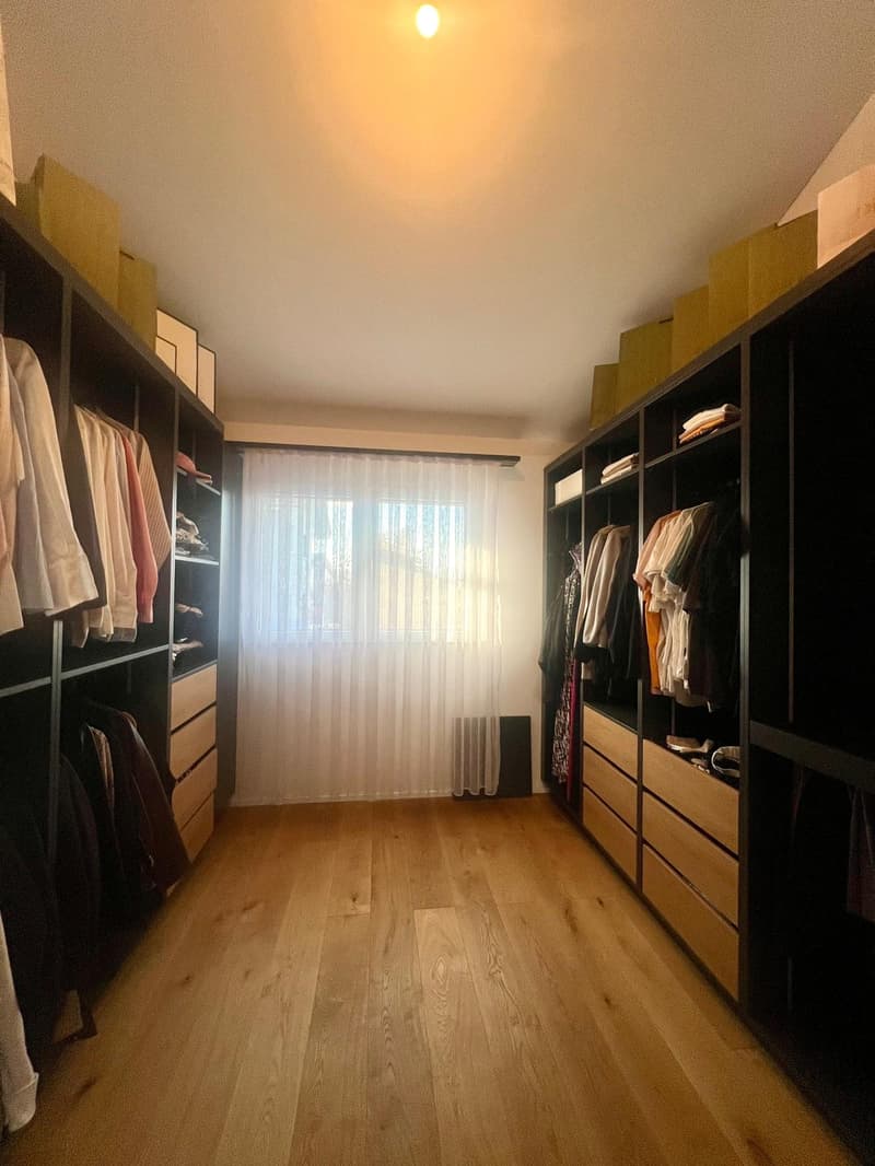 Wooden floor, tall wardrobes on either side, white curtains, natural light
