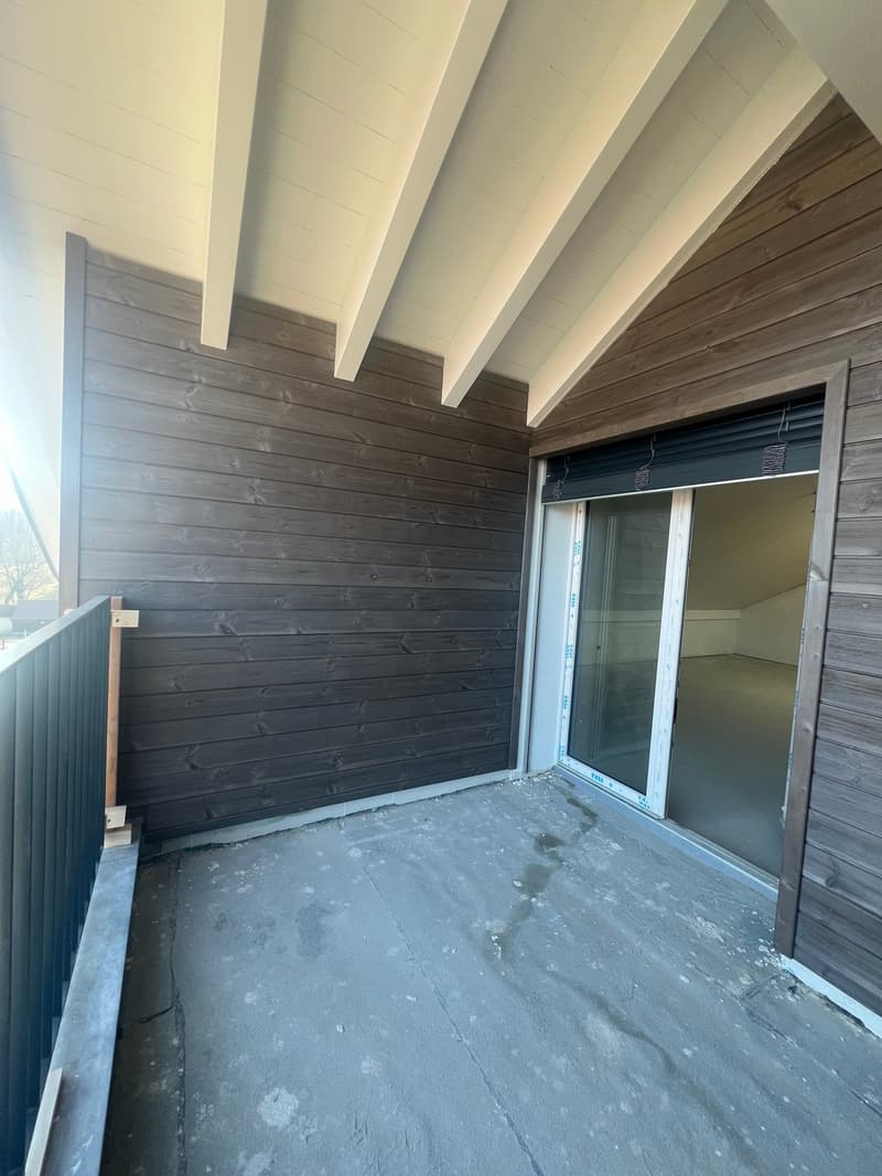 Wooden walls, concrete floor, glass sliding door, black railings, open balcony