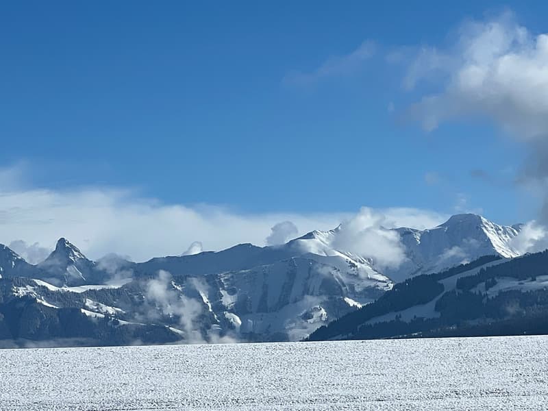mountain range with snow, clear blue sky, fog, flat landscape