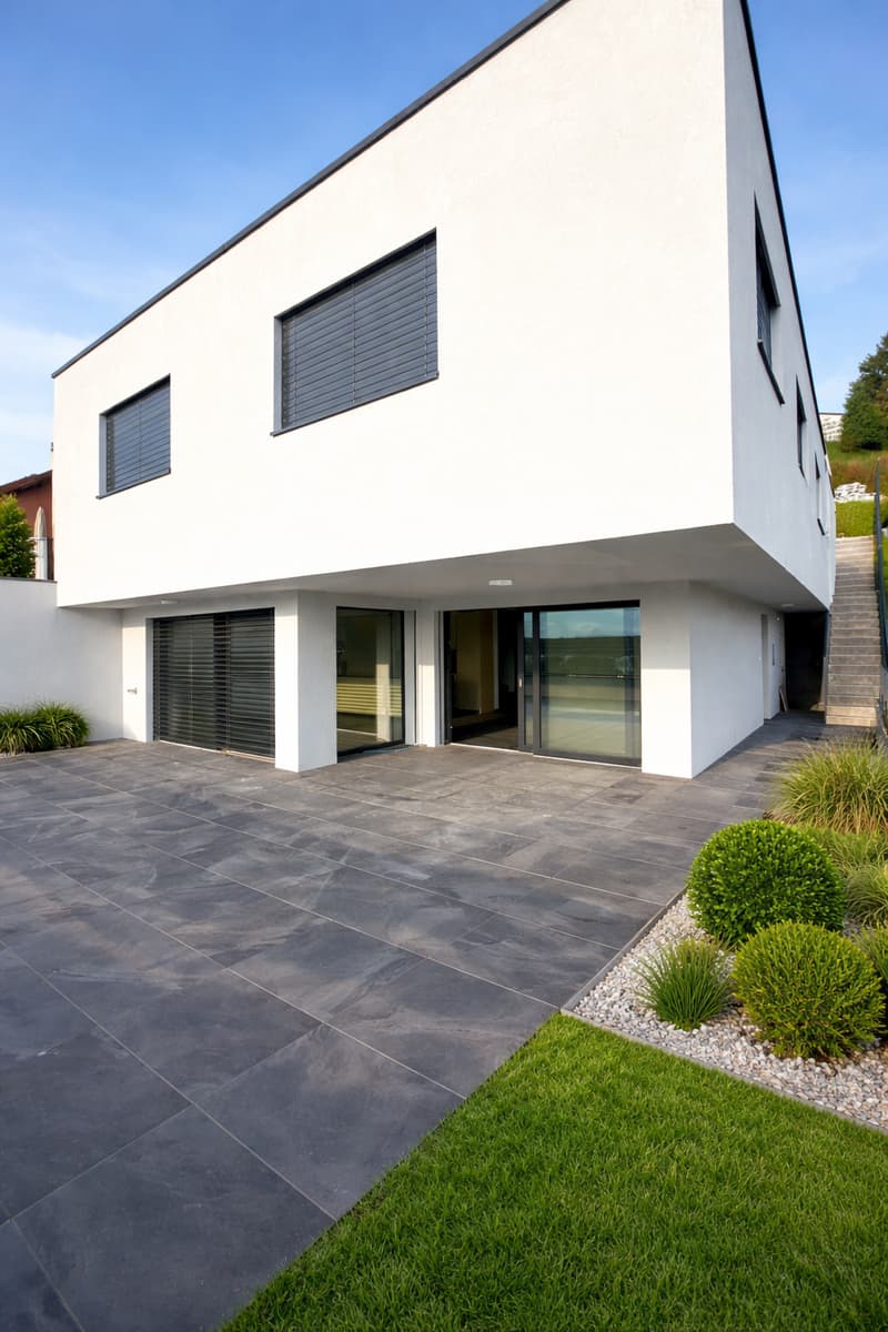 modern white house, large windows, garage, paved driveway, landscaped garden