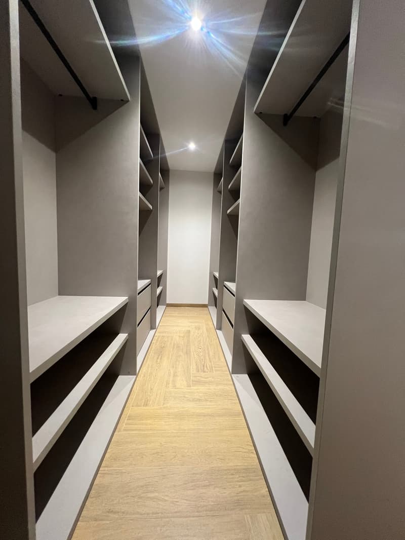 walkway between two large wardrobes, wooden floor, gray walls, white shelves, drawers, lights
