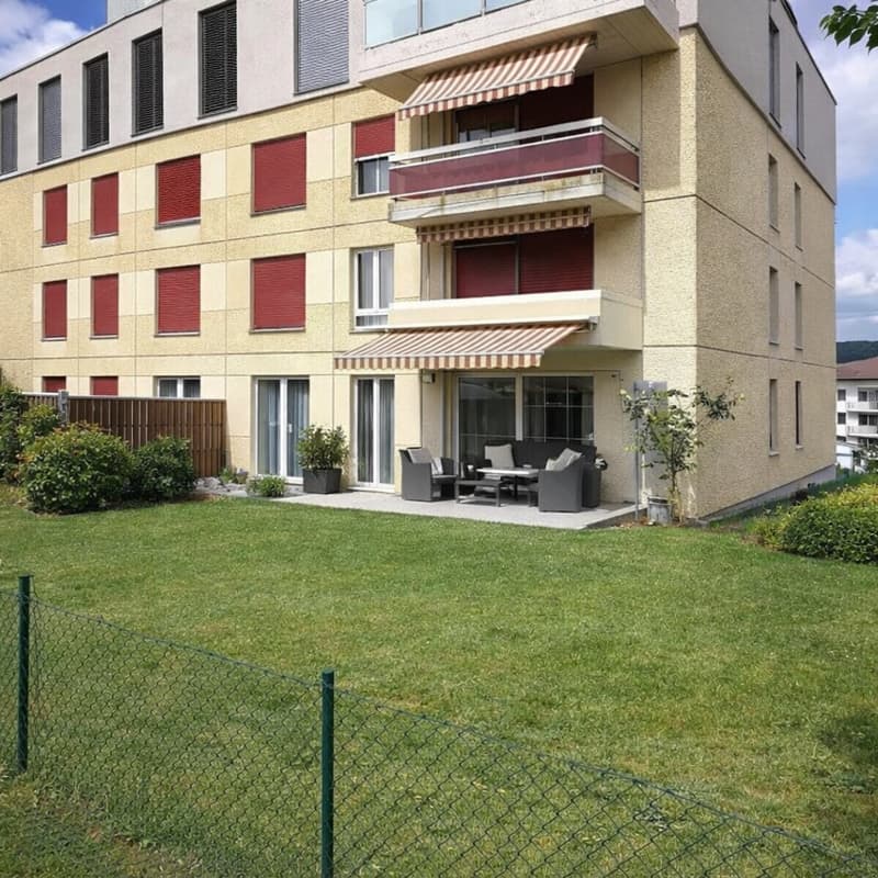 3 story building, yellow exterior, red shutters, balcony, patio with seating, garden