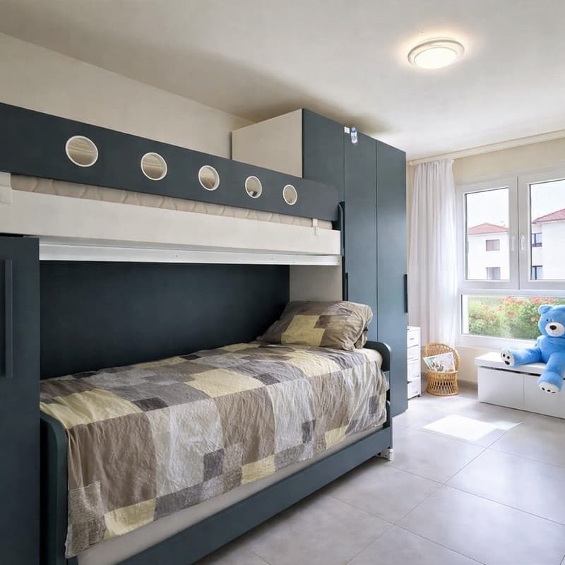A bedroom with a bunk bed, a pillow, a blanket, a cabinet, a white shelf, a basket, a stuffed toy, a window, and a ceiling light.