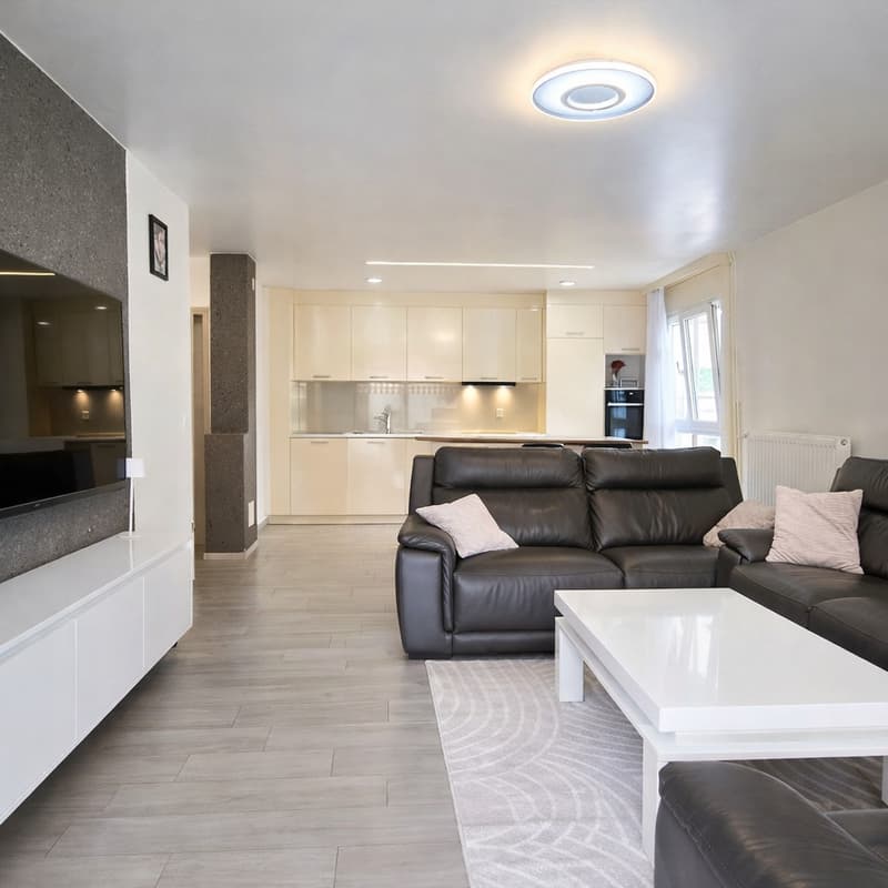 modern living room, black leather sofa, white coffee table, large flat screen TV, white cabinets, white radiator, wooden floor