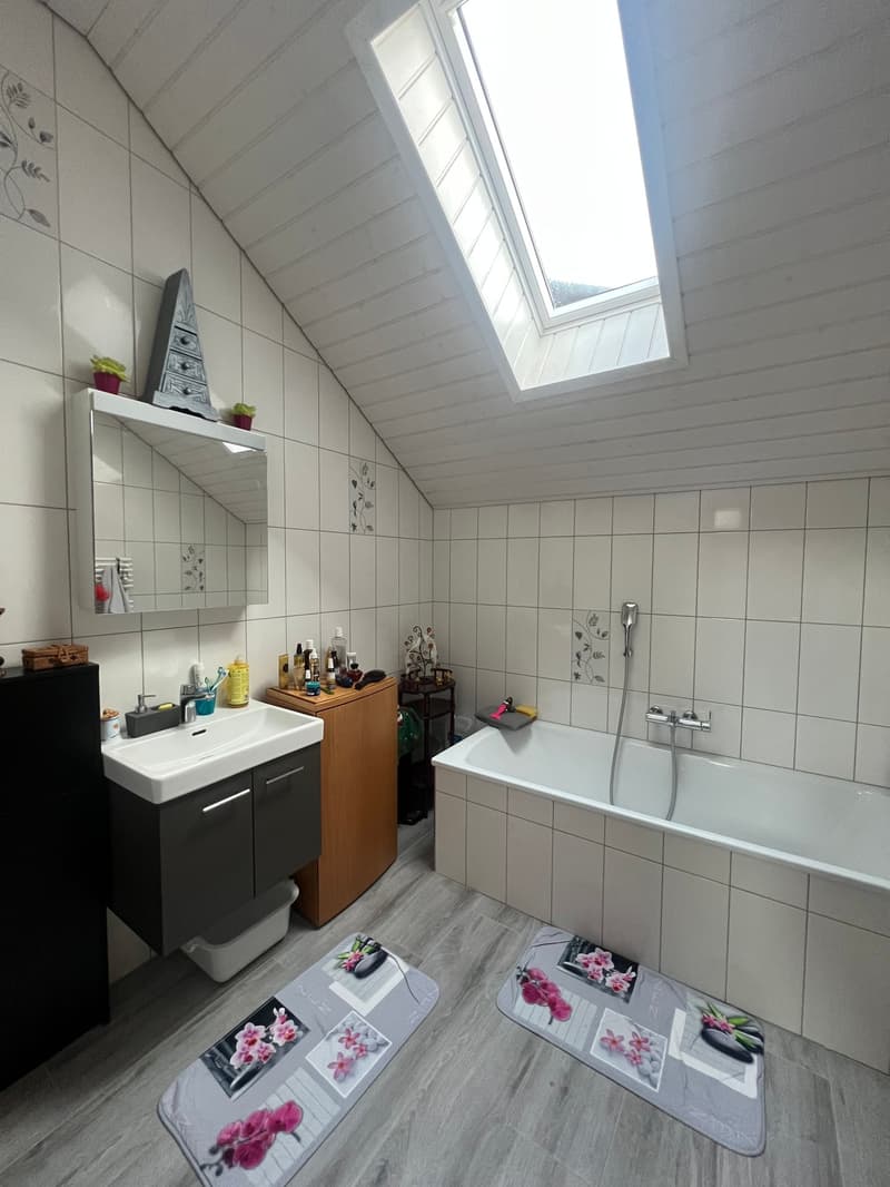 Bathroom with bathtub, sink, mirror, wooden cabinet, and a skylight