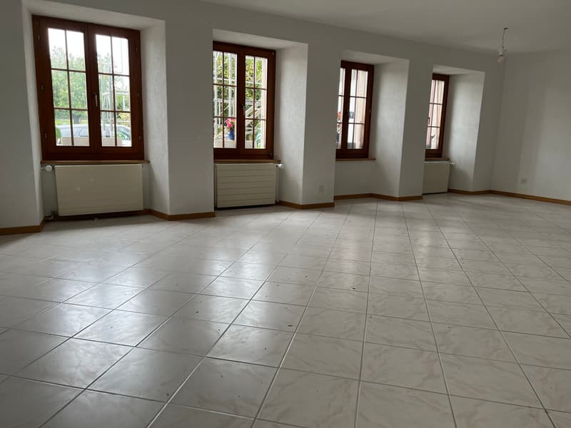 Empty room with white tiles, three windows, and radiators