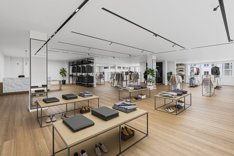 Open space clothing store with tables, clothes racks, hardwood floors, modern lighting