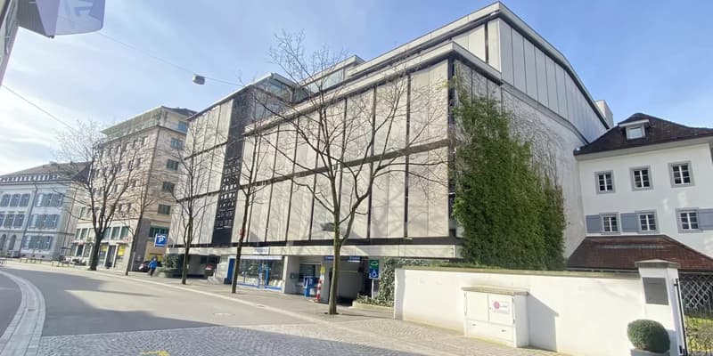 Modern building with glass windows, white walls, and a parking sign