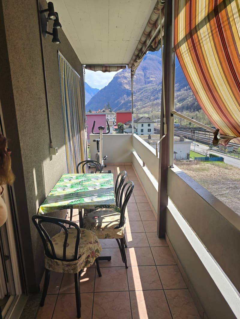 Balcony with table and chairs, exercise bike, tiled floor, curtains, view of mountains