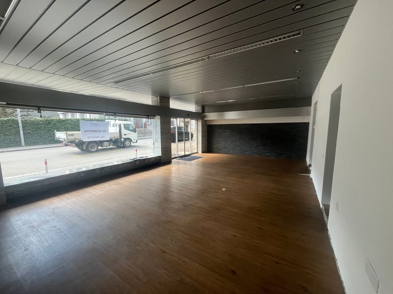 large room, wooden floors, glass walls, black wall, no furniture