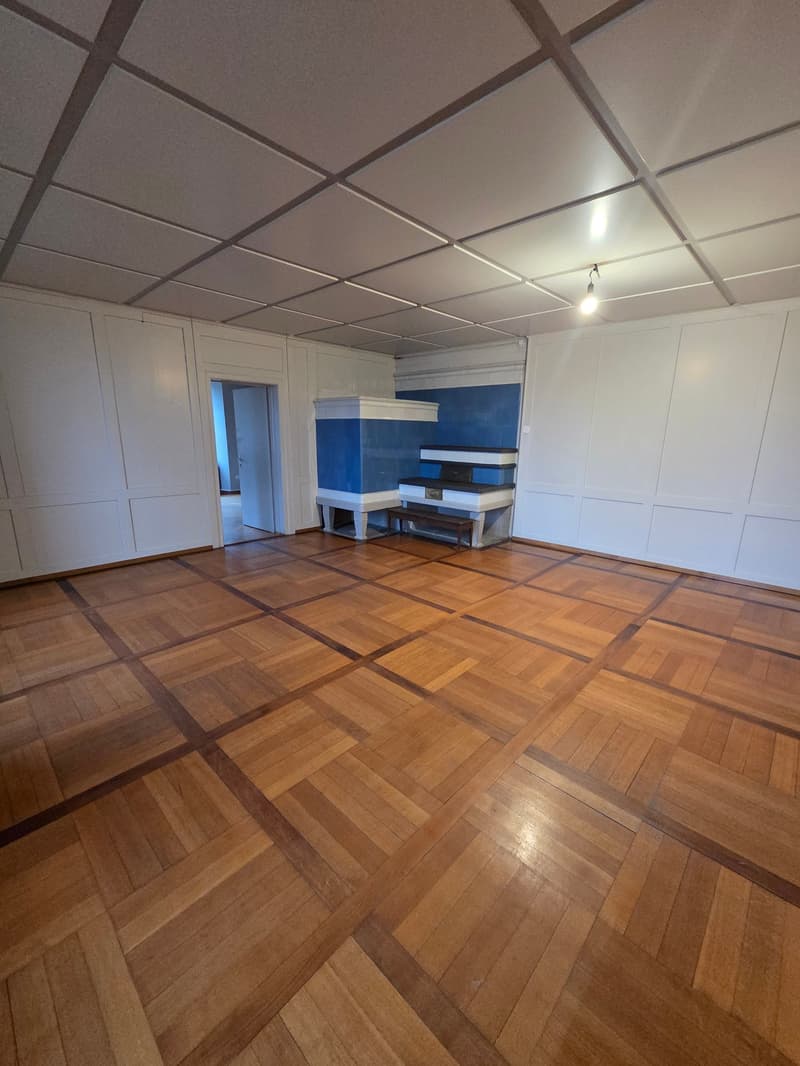 Hardwood floors, white walls, ceiling with grid, fireplace, bench, entrance