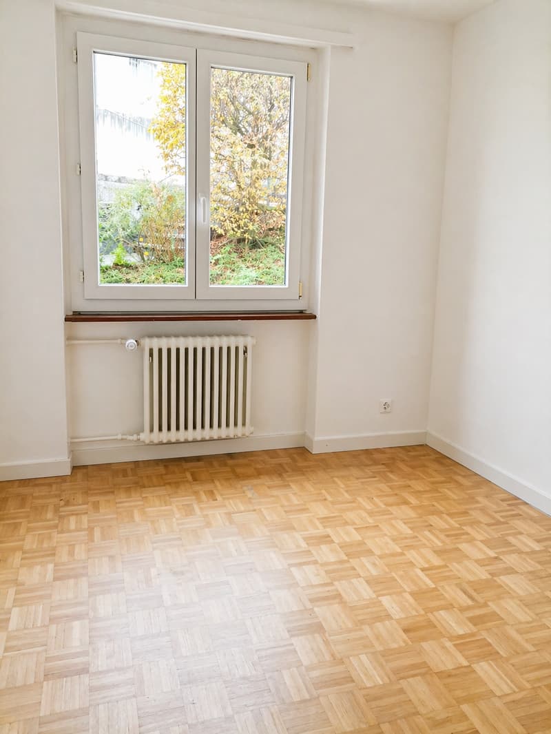 empty room, wooden parquet floor, white walls, large window, white radiator