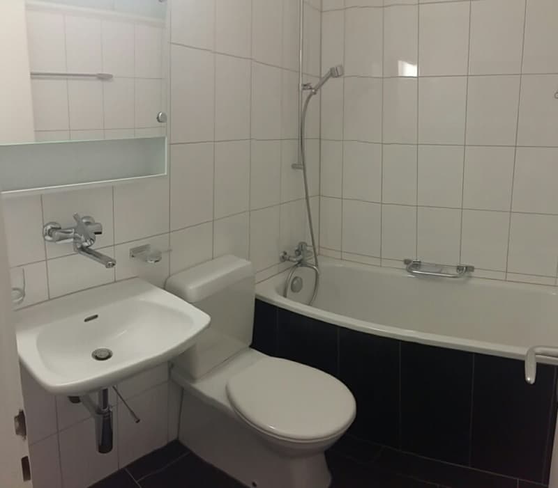 Bathroom with white tiles, white sink, white toilet, bathtub, shower head