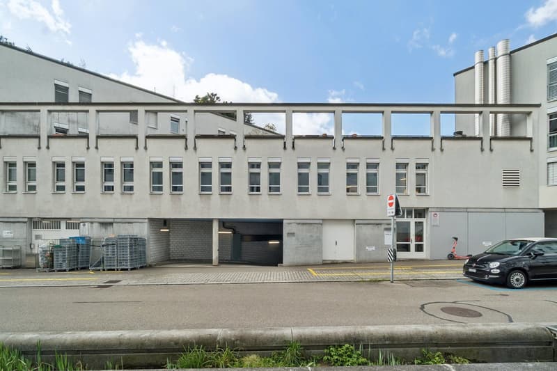 Modern building with multiple windows, garage entrance, and a car parked in front