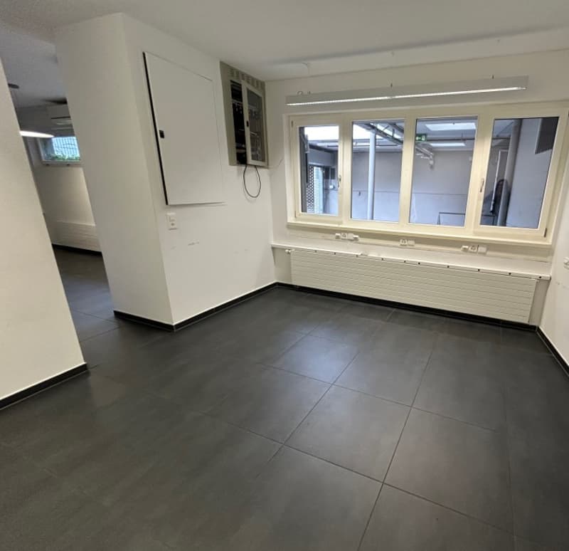 empty room, white walls, tiled floor, large windows, radiator, wiring equipment in corner