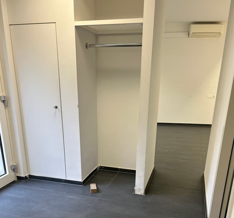 white closet, tile floor, small piece of wood on floor