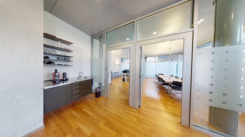 modern office room with wood floors, glass walls, cabinets, and a desk