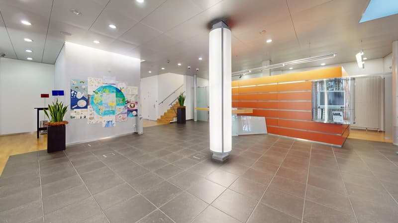 modern office with white ceiling, white walls, tiled floor, gray ceiling lights, glass and orange reception counter, wooden staircase, wooden floor, potted plants
