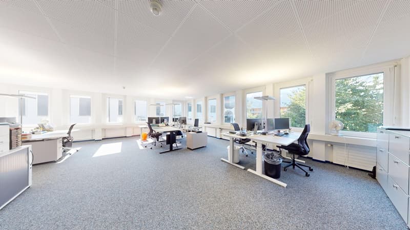 modern office layout with desks, chairs, computers, and a few storage units
