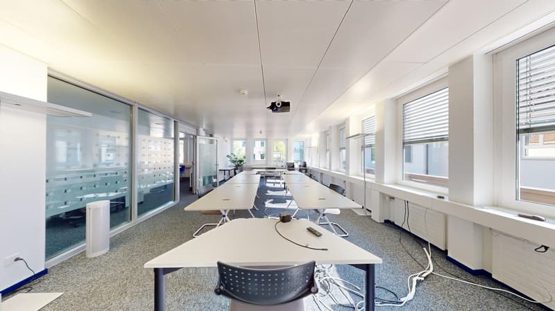 Empty conference room with white desks, chairs, glass windows, projector.
